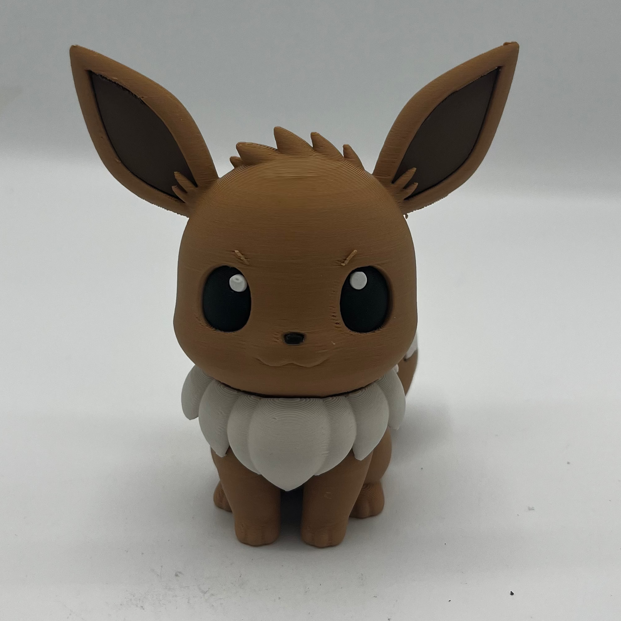 A small brown and white Eevee figurine standing against a plain light background.