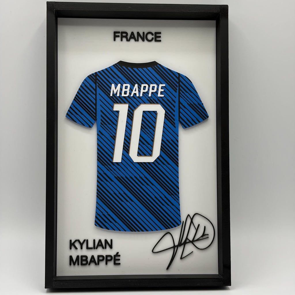 A framed Kylian Mbappé France soccer jersey display featuring a blue and black striped jersey with 'MBAPPE 10' on the back, inside a black shadowbox frame with 'FRANCE' at the top and 'KYLIAN MBAPPEÉ' with a signature at the bottom.