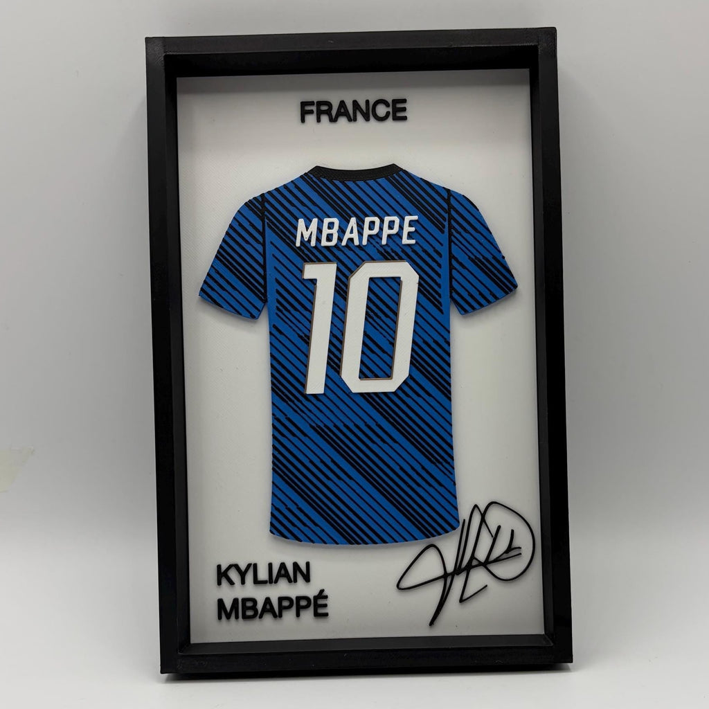 A framed Kylian Mbappé France soccer jersey display featuring a blue patterned jersey with the number 10, signed in black marker, inside a black shadowbox frame on a white background.