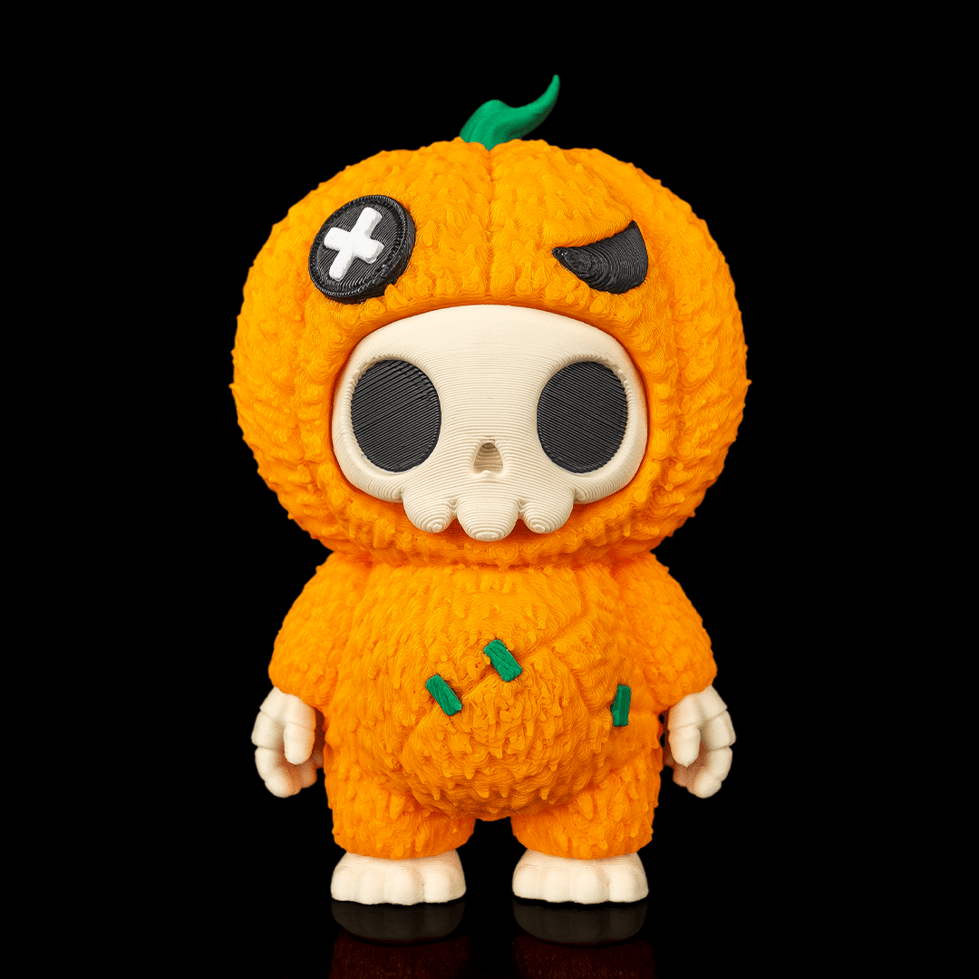 A stylized collectible figure resembling a pumpkin character in a fuzzy orange knit-like costume, standing against a solid black background. The figure has a cream-colored skull face, black circular eyes, a green stem, and small green stitched details on the body.