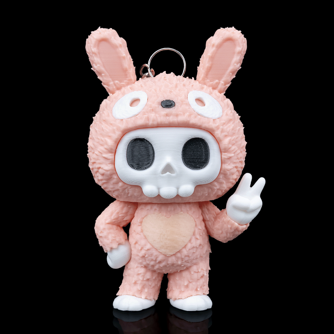 Pink 3D printed toy with skull design on a black background