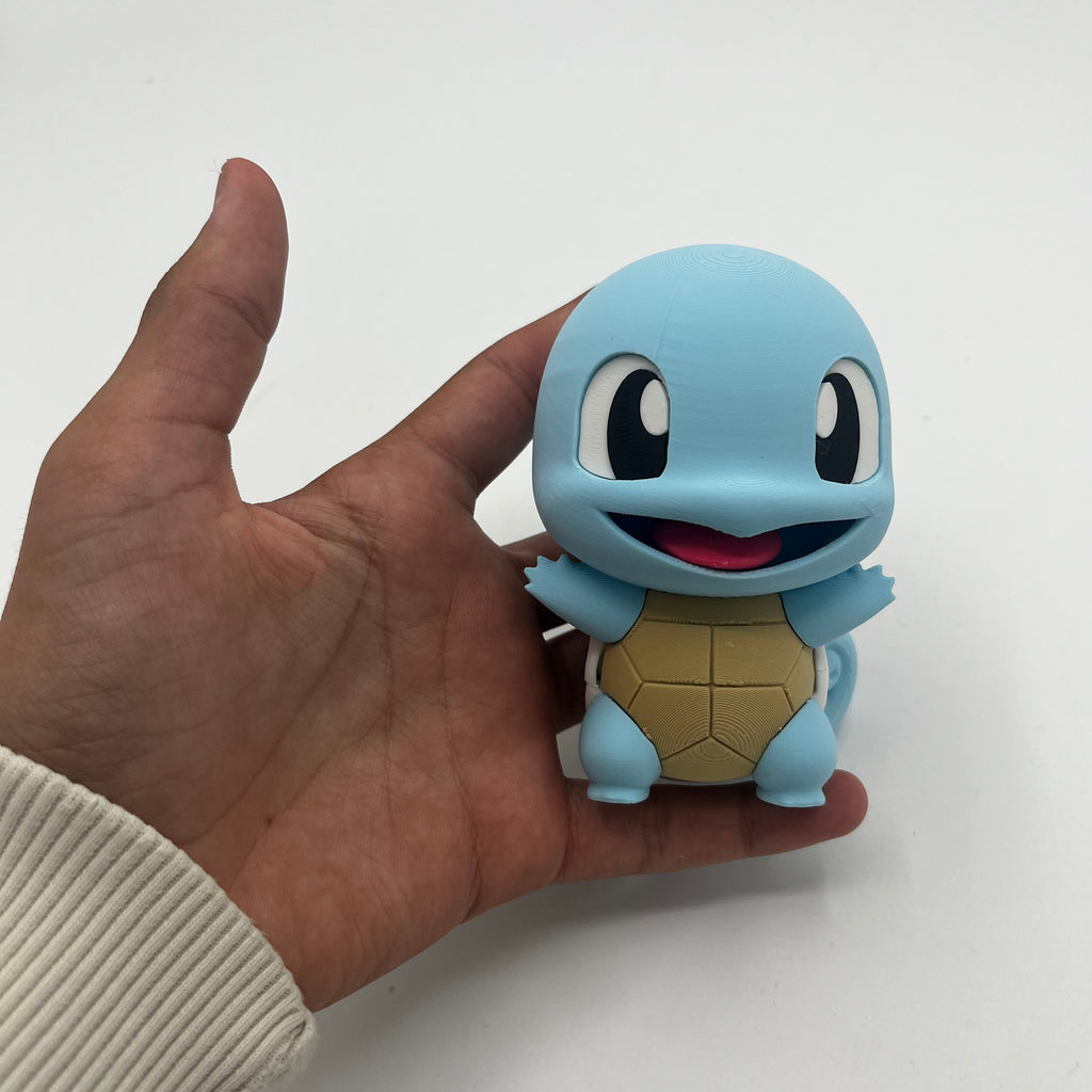 A small blue Squirtle figurine held in a person's hand against a plain white background.