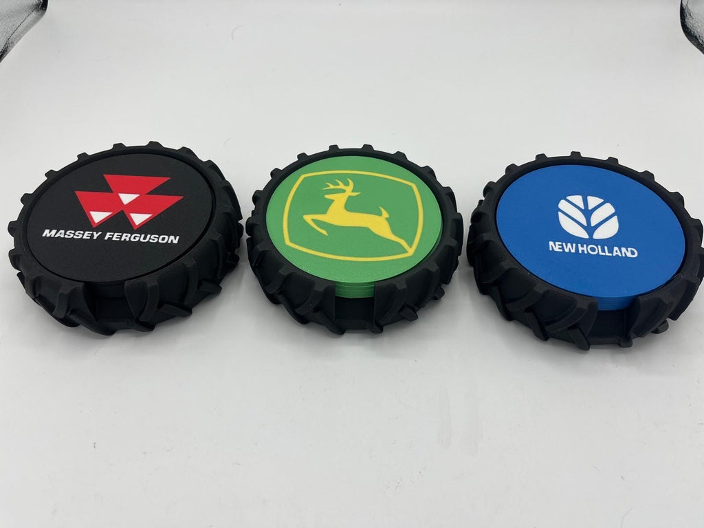 Three tractor-style wheels with coasters displayed side by side on a white surface, featuring Massey Ferguson, John Deere, and New Holland logos.