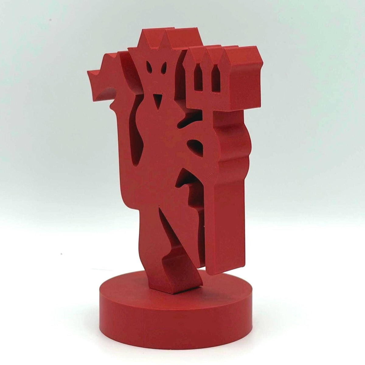 A red abstract geometric sculpture standing on a round cylindrical base, photographed against a plain light grey studio background.